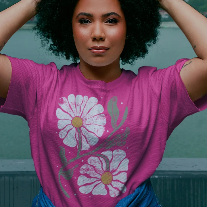 Woman wearing a pink t-shirt with floral designs, standing outdoors.